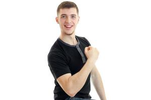 un' allegro giovane uomo nel un' nero maglietta Spettacoli il muscoli di il braccio e ride avvicinamento foto