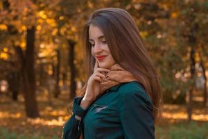 sorridente ragazza sta nel il parco e guardare giù foto