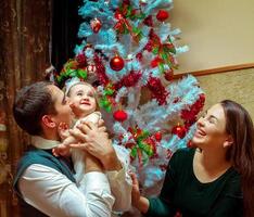 contento Natale famiglia con poco bambino ragazza. genitori sorridente e avendo divertimento con bambino foto