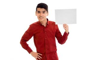un' giovane tipo nel il rosso camicia sembra dritto e mantiene un' bianca foglio di carta foto