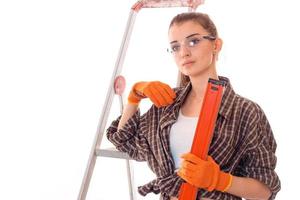 giovane bello donna con buio capelli nel uniforme fa lavori di ristrutturazione con utensili nel sua mani isolato su bianca sfondo foto