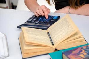 femmina mano con calcolatrice e libro foto