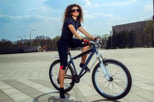 gli sport donna nel occhiali da sole su bicicletta foto