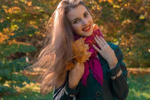 bellissimo ragazza sta sorridente nel il parco e sua capelli nel il vento foto