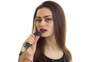un' avvicinamento ritratto di attraente giovane cantante con un' microfono foto
