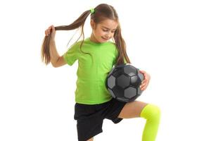 atletico poco ragazza nel un' verde maglietta con il palla nel mano foto