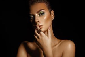 fascino alto contrasto giovane donna con verde colori trucco su nero sfondo foto