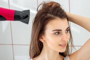 un' ragazza si asciuga capelli nel il bagno foto