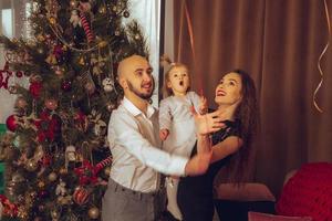 elegante contento famiglia con figlia celebrare nuovo anno e Natale insieme foto