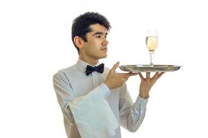 sbalorditivo snello giovane Cameriere sollevato il suo mani nel un' vassoio con un' bicchiere di Champagne foto