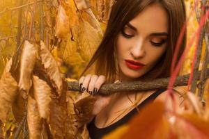 sensuale giovane ragazza con rosso labbra in posa nel autunno le foglie foto