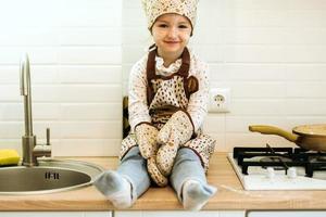 ritratto carino poco cuoco casalingo ragazza nel bianca cucina. foto