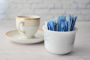 zucchero sostituto dolcificante nel un' pacchetto e tazza di tè su tavolo foto