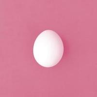 uno bianca Pasqua uovo su un' luminosa sfondo Immagine tonica nel Viva magenta, colore di il anno foto