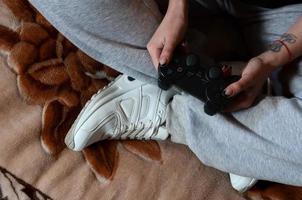 moderno nero gioco controllore nel il mani di un' seduto giovane ragazza foto