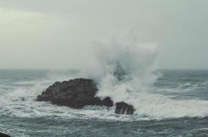 spruzzi acqua al di sopra di roccia nel oceano paesaggio foto