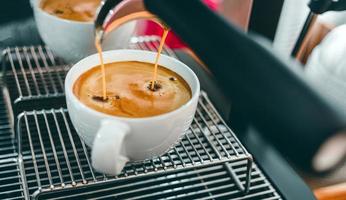 avvicinamento di caffè estrazione a partire dal il caffè macchina con un' portafilter scrosciante caffè in un' tazza, caffè espresso scrosciante a partire dal caffè macchina a il caffè negozio foto