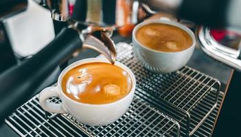 avvicinamento di caffè estrazione a partire dal il caffè macchina con un' portafilter scrosciante caffè in un' tazza, caffè espresso scrosciante a partire dal caffè macchina a il caffè negozio foto