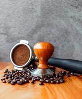 attrezzatura di barista caffè attrezzo portafilter con manomettere e buio arrostito caffè fagioli su di legno tavolo nel un' caffè negozio foto