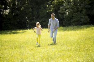 padre che insegue la sua piccola figlia mentre gioca nel parco foto