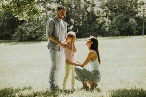 giovane famiglia felice con la piccola figlia carina che si diverte nel parco in una giornata di sole foto