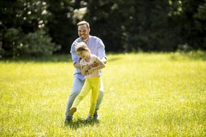 padre che insegue la sua piccola figlia mentre gioca nel parco foto