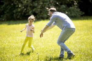 padre che insegue la sua piccola figlia mentre gioca nel parco foto