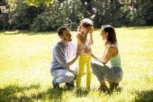 giovane famiglia felice con la piccola figlia carina che si diverte nel parco in una giornata di sole foto