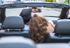 amici avendo divertimento a auto viaggio in giro il mondo. coppia nel amore con braccia su su un' convertibile macchina. foto