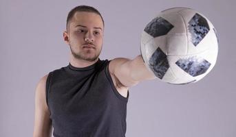 giovane contento uomo 20s fan supporto calcio sport squadra hold nel mano calcio sfera. isolato su pianura solido grigio sfondo foto