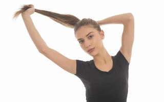 giovane attraente sorridente donna Tenere sua forte capelli foto