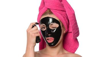 bellissimo femmina modello con nero facciale cosmetico maschera. isolato su grigio sfondo foto