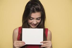 giovane sorridente donna Tenere un' vuoto foglio di carta per pubblicità foto