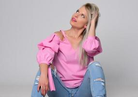 ritratto di bellissimo giovane donna nel carino rosa camicia e blu jeans in posa nel studio. concetto di bellezza, emozioni, facciale espressione, stile di vita, moda, gioventù cultura foto