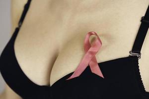 Salute cura, medicina e Seno cancro consapevolezza concetto. giovane donna nel reggiseno con rosa nastro simbolo foto