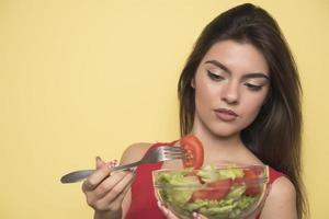 ritratto di un' contento giocoso ragazza mangiare fresco insalata a partire dal un' arco foto