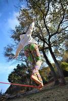 giovane donna equilibratura e salto su slackline. donna a passeggio, salto e equilibratura su corda foto