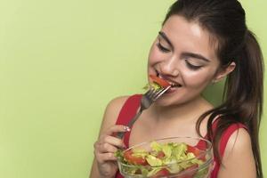 ritratto di un' contento giocoso ragazza mangiare fresco insalata a partire dal un' ciotola foto