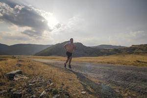 sportivo uomo corridore in esecuzione su montagna altopiano nel estate foto