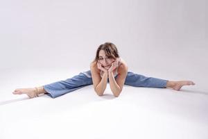 ritratto di bellissimo giovane donna con atletico flessibile corpo fare gamba allungamento. isolato foto