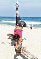 in forma sportivo donna praticante acrobatico yoga su il spiaggia foto