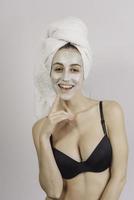 terme donna l'applicazione facciale argilla maschera. bellezza trattamenti. avvicinamento ritratto di bellissimo ragazza con un' asciugamano su sua testa l'applicazione facciale maschera. foto