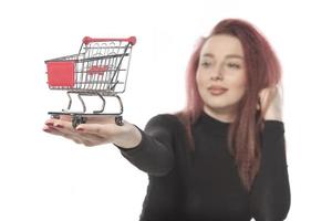 contento femmina Tenere credito carte e un' piccolo vuoto shopping carrello isolato su bianca sfondo foto