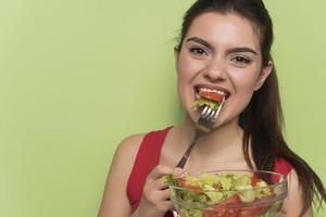 ritratto di un' contento giocoso ragazza mangiare fresco insalata a partire dal un' arco foto