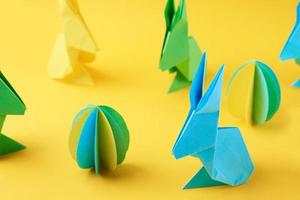 carta origami esater conigli e colorato uova su giallo sfondo foto