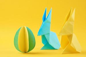 Due carta origami esater conigli e colorato uovo su giallo sfondo foto