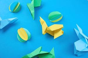 carta origami esater conigli e colorato uova su blu sfondo foto