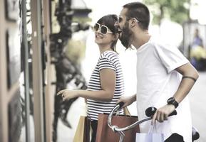 ritratto di allegro caucasico giovane coppia uomo e donna Tenere molti carta borse dopo shopping mentre a piedi e parlando su strada. contento famiglia coppia con pacchi all'aperto. acquisto concetto foto