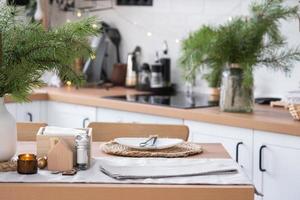 festivo Natale arredamento nel bianca cucina, festivo colazione, bianca scandi interno. il figura di un' accogliente Casa ione il impostato tavolo. nuovo anno, umore, accogliente casa. copia spazio foto