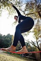 donna equilibratura sua camminare su un' perdere corda legato fra Due alberi. donna praticante allentamento corda a piedi nel un' parco. foto